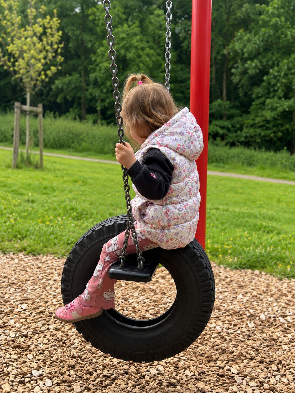 Kind schaukelt auf einem Reifen auf dem Spielplatz